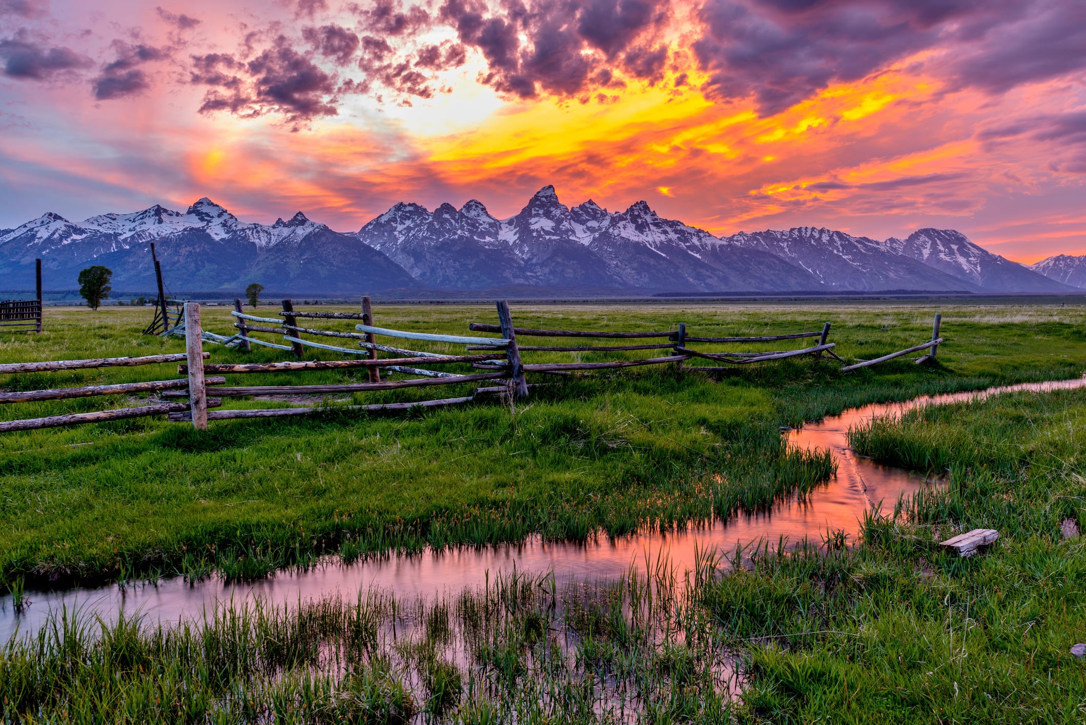 jackson hole guide: A colorful spring sunset at Teton Range, seen from an abandoned old ranch in Mormon Row historic district, in Grand Teton National Park, Wyoming, USA.