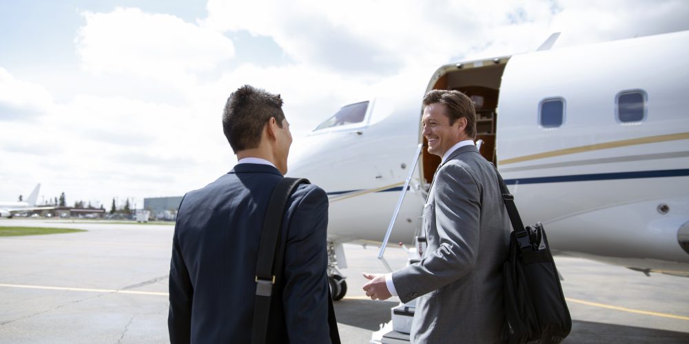 Businessmen walking on airport tarmac toward corporate jet