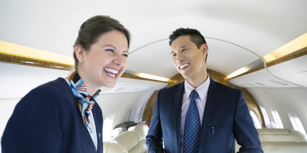 Businessman and flight attendant laughing on corporate jet