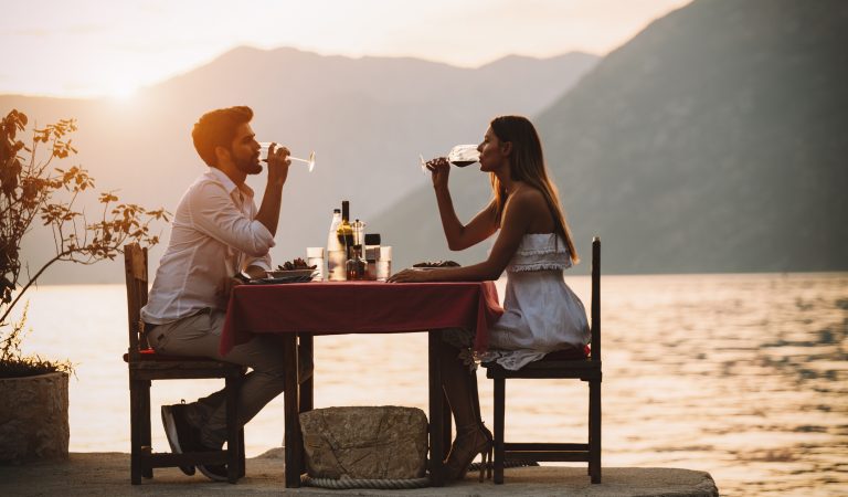 Couple is having a private event dinner on a tropical beach during sunset time. Honeymoon travel concept